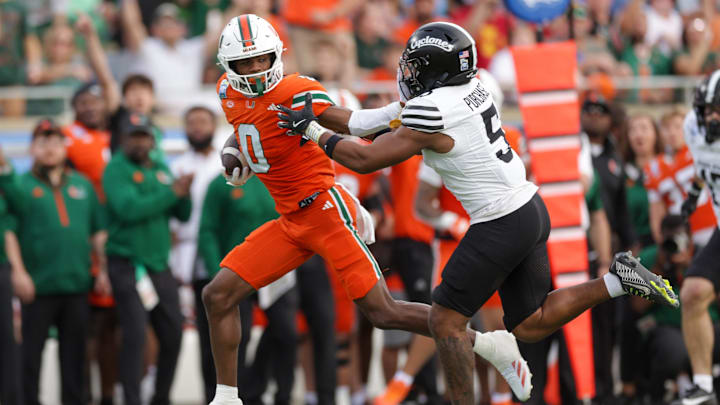 Dec 28, 2024; Orlando, FL, USA; Miami Hurricanes wide receiver Joshisa Trader (0) holds off Iowa State Cyclones defensive back Myles Purchase (5) in the second quarter during the Pop Tarts bowl at Camping World Stadium. Mandatory Credit: Nathan Ray Seebeck-Imagn Images