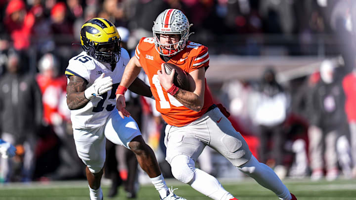 Ohio State quarterback Will Howard (18) runs against Michigan linebacker Ernest Hausmann (15) during the first half at Ohio Stadium in Columbus, Ohio on Saturday, Nov. 30, 2024.