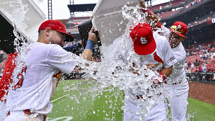 Sep 12, 2024; St. Louis, Missouri, USA;  St. Louis Cardinals second baseman Thomas Saggese (25) is doused with water by center fielder Michael Siani (63) and left fielder Lars Nootbaar (21) after collecting his first career hit and his first rbi in a victory over the Cincinnati Reds at Busch Stadium. Mandatory Credit: Jeff Curry-Imagn Images