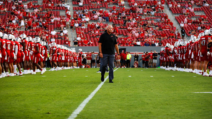 Aug 29, 2024; Raleigh, North Carolina, USA; North Carolina State Wolfpack head coach Dave Doeren between his players before the first half of the game against Western Carolina Catamounts at Carter-Finley Stadium. Mandatory Credit: Jaylynn Nash-Imagn Images