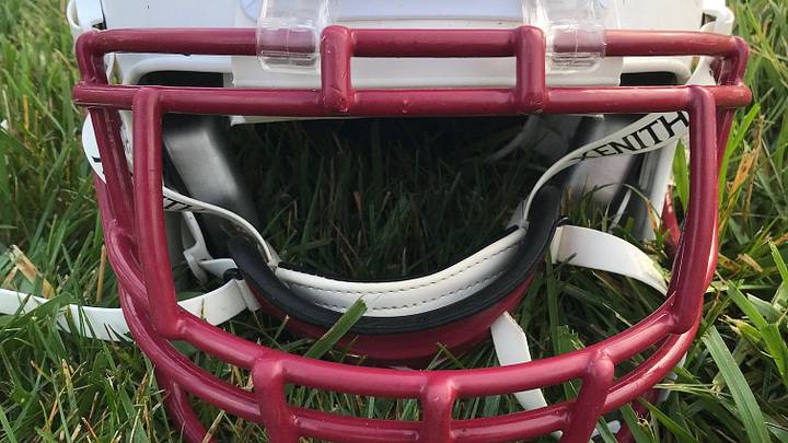 A high school football helmet resting in the grass. A high school football helmet resting in the grass.