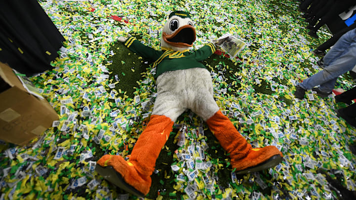 Dec 7, 2024; Indianapolis, IN, USA; The Oregon Duck mascot makes snow angels in confetti after defeating the Penn State Nittany Lions to win the Big Ten Championship in the 2024 Big Ten Championship game at Lucas Oil Stadium. Mandatory Credit: Robert Goddin-Imagn Images