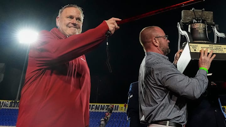 Arkansas coach Sam Pittman points to his players and Razorback fans with his cane as he is presented with the AutoZone Liberty Bowl trophy after the Hogs defeated Texas Tech 36-26 in Memphis, Tenn.