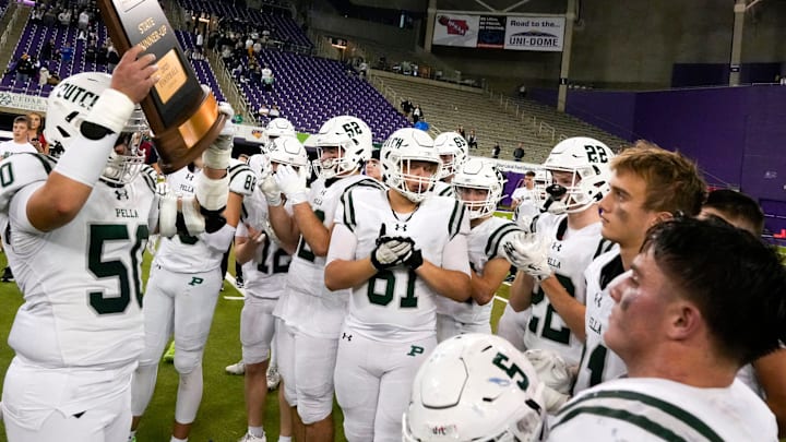 Pella's Keegan Miller (5) lifts the consolation trophy Nov. 20, 2025 after the Class 4A state football championship against the Xavier Saints at the UNI-Dome in Cedar Falls, Iowa.