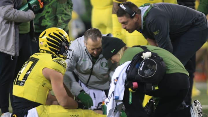 Oregon quarterback Bo Nix, left, sits in the turf after being injured on a fourth quarter play