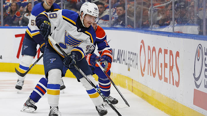 Dec 7, 2024; Edmonton, Alberta, CAN; St. Louis Blues defensemen Scott Perunovich (48) clears the puck against Edmonton Oilers forward Mattias Janmark (13) during the third period at Rogers Place. Mandatory Credit: Perry Nelson-Imagn Images