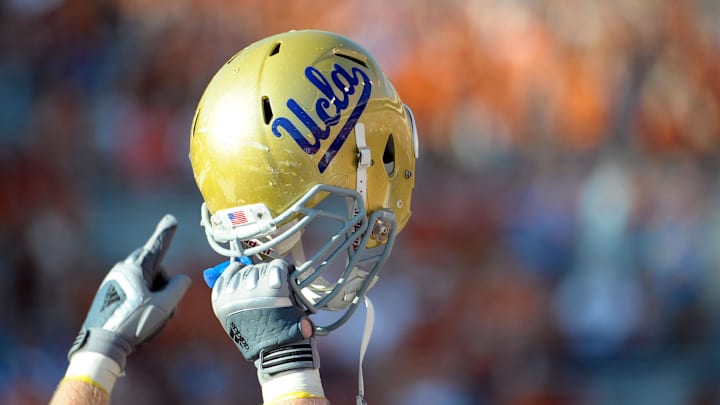 Sept 25, 2010; Austin, TX, USA; A member of the UCLA Bruins holds up his helmet to acknowledge their fans against the Texas Longhorns during the fourth quarter at Texas Memorial Stadium. UCLA beat Texas 34-12. Mandatory Credit: Brendan Maloney-Imagn Images