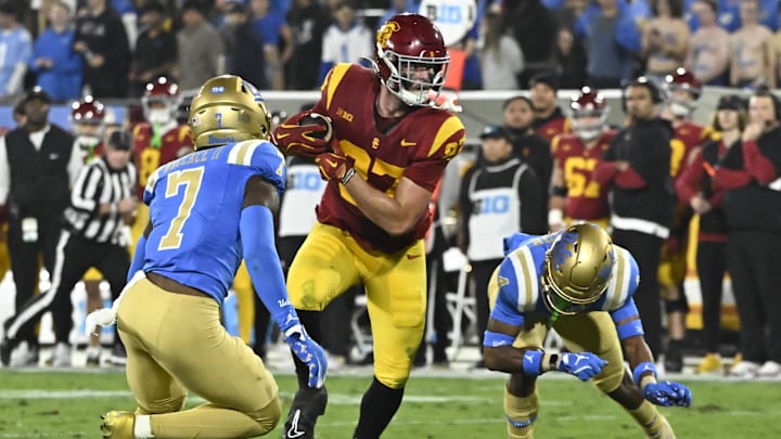 Nov 23, 2024; Pasadena, California, USA; USC Trojans tight end Lake McRee (87) runs a pass between UCLA Bruins defensive back K.J. Wallace (7) and defensive back Bryan Addison (4) during the second quarter at Rose Bowl. Mandatory Credit: Robert Hanashiro-Imagn Images