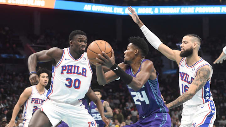 Dec 3, 2024; Charlotte, North Carolina, USA;  Charlotte Hornets forward Brandon Miller (24) looks to shoot through the defense of Philadelphia 76ers center Adam Bona (30) and forward Caleb Martin (11) during the second half at the Spectrum Center. Mandatory Credit: Sam Sharpe-Imagn Images