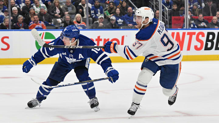Nov 16, 2024; Toronto, Ontario, CAN;  Edmonton Oilers forward Connor McDavid (97) shoots the puck against Toronto Maple Leafs forward Mitch Marner (16) in overtime at Scotiabank Arena. Mandatory Credit: Dan Hamilton-Imagn Images