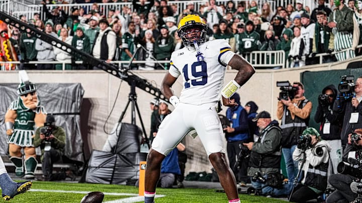 Michigan quarterback Bryce Underwood celebrates a touchdown by posing as the Paul Bunyan Trophy against Michigan State during the first half at Spartan Stadium in East Lansing on Saturday, October 25, 2025.
