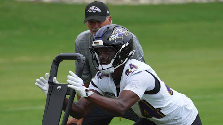 Jul 24, 2025; Owings Mills, MD, USA; Baltimore Ravens coach Chuck Pagano and safety Malaki Starks (24) work on drills during training camp at the Under Armour Performance Center. Mandatory Credit: Mitch Stringer-Imagn Images