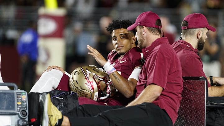 Nov 18, 2023; Tallahassee, Florida, USA; Florida State Seminoles quarterback Jordan Travis (13) waves to fans while being carted off after an injury against the North Alabama Lions during the first quarter at Doak S. Campbell Stadium. Mandatory Credit: Morgan Tencza-Imagn Images