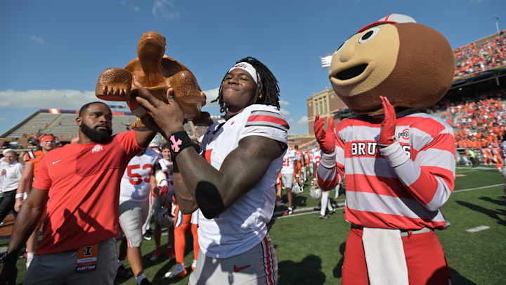 Oct 11, 2025; Champaign, Illinois, USA; Ohio State Buckeyes wide receiver Jeremiah Smith (4) celebrates winning the Illinibuck Trophy with Ohio State Buckeyes mascot Brutus following a win over the Illinois Fighting Illini at Memorial Stadium. Mandatory Credit: Ron Johnson-Imagn Images