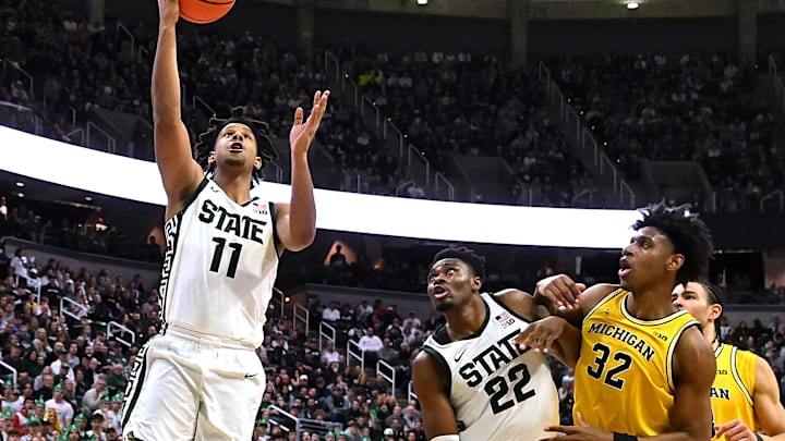 Jan 30, 2024; East Lansing, Michigan, USA; Michigan State Spartans guard A.J. Hoggard (11) gets a slashing layup to go in while teammate center Mady Sissoko (22) and Michigan Wolverines forward Tarris Reed Jr. (32) battle for position during the second half at Jack Breslin Student Events Center. Mandatory Credit: Dale Young-Imagn Images