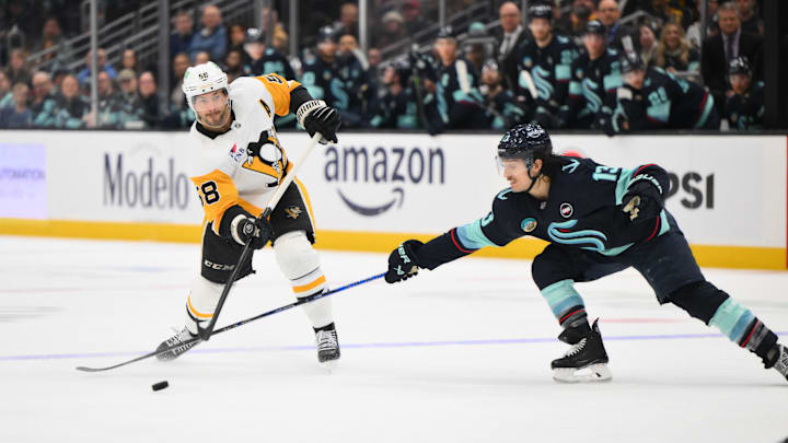 Jan 25, 2025; Seattle, Washington, USA; Pittsburgh Penguins defenseman Kris Letang (58) passes the puck past Seattle Kraken left wing Brandon Tanev (13) during the second period at Climate Pledge Arena. Mandatory Credit: Steven Bisig-Imagn Images