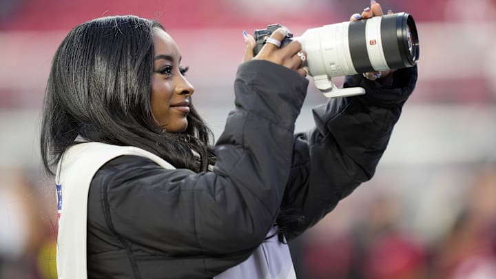Dec 28, 2025; Santa Clara, California, USA; American gymnast Simone Biles takes photographs on the sideline before the game between the San Francisco 49ers and the Chicago Bears at Levi's Stadium. Dec 28, 2025; Santa Clara, California, USA; American gymnast Simone Biles takes photographs on the sideline before the game between the San Francisco 49ers and the Chicago Bears at Levi's Stadium.