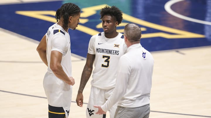 Feb 18, 2026; Morgantown, West Virginia, USA; West Virginia Mountaineers head coach Ross Hodge talks with guard Jasper Floyd (1) and  guard Honor Huff (3) during the second half against the Utah Utes at Hope Coliseum. Mandatory Credit: Ben Queen-Imagn Images
