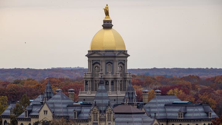 Nov 8, 2025; South Bend, Indiana, USA; The Golden Dome atop the Main Building with fall foliage before the Notre Dame Fighting Irish vs. the Navy Midshipmen logos at Notre Dame Stadium. Mandatory Credit: Michael Caterina-Imagn Images