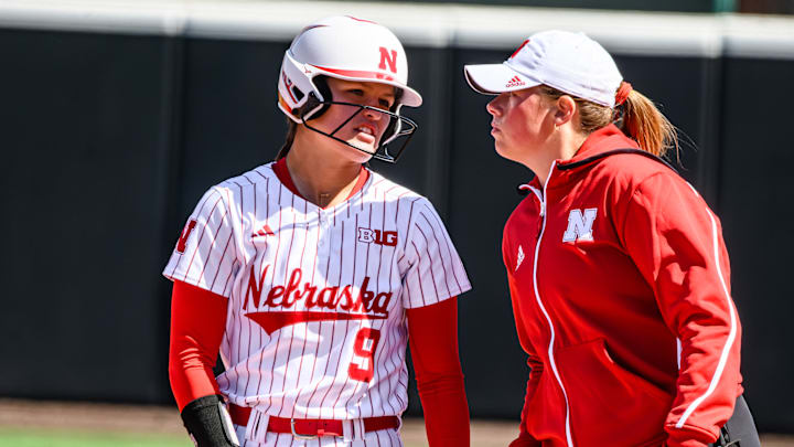 Hannah Camenzind (9) chats with assistant coach Olivia Ferrell after a single. 