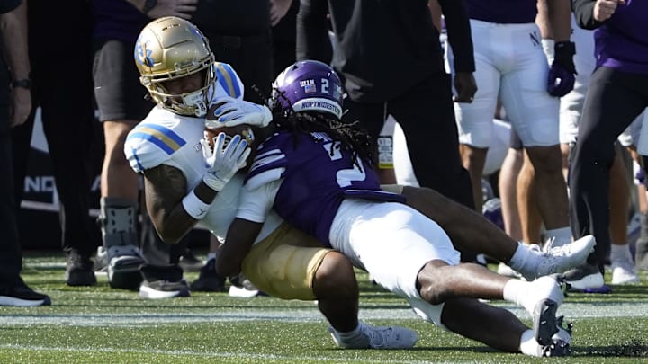 Sep 27, 2025; Evanston, Illinois, USA; Northwestern Wildcats defensive back Fred Davis II (2) tackles UCLA Bruins wide receiver Rico Flores Jr. (1) during the first half at Northwestern Medicine Field at Martin Stadium. Mandatory Credit: David Banks-Imagn Images