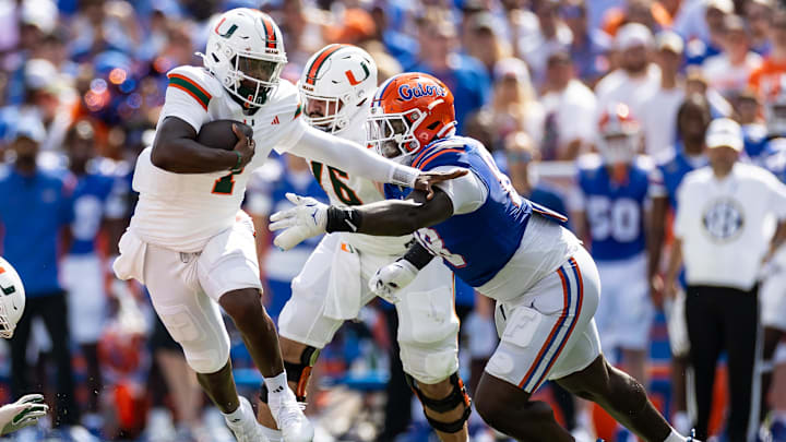 Aug 31, 2024; Gainesville, Florida, USA; Miami Hurricanes quarterback Cam Ward (1) runs past Florida Gators defensive lineman Caleb Banks (88) during the first half at Ben Hill Griffin Stadium. Mandatory Credit: Matt Pendleton-Imagn Images