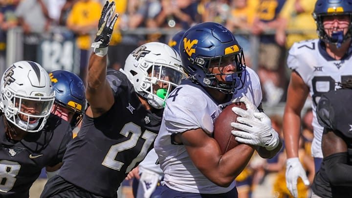 Oct 28, 2023; Orlando, Florida, USA; West Virginia Mountaineers running back CJ Donaldson Jr. (4) carries the ball as UCF Knights defensive back Nikai Martinez (21) move in for the tackle during the second half at FBC Mortgage Stadium. Mandatory Credit: Mike Watters-Imagn Images