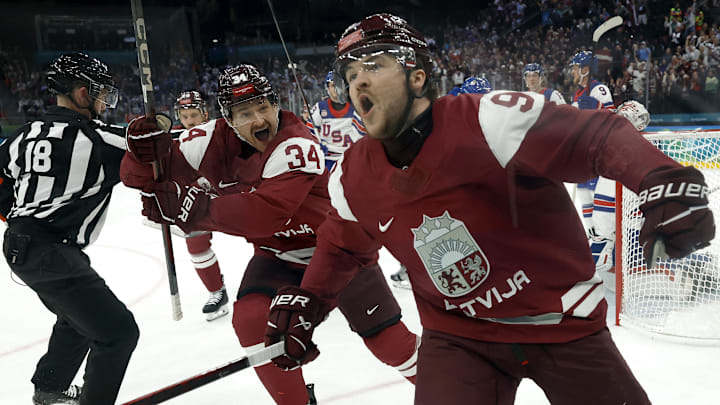 Feb 12, 2026; Milan, Italy; Renars Krastenbergs of Latvia celebrates scoring their first goal with Eduards Tralmaks of Latvia in men's ice hockey group C play during the Milano Cortina 2026 Olympic Winter Games at Milano Santagiulia Ice Hockey Arena. Mandatory Credit: Geoff Burke-Imagn Images