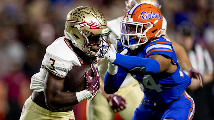 Florida State Seminoles running back Trey Benson (3) rushes with the ball while Florida Gators linebacker Mannie Nunnery (34) attempts to tackle during the first half at Steve Spurrier Field at Ben Hill Griffin Stadium in Gainesville, FL on Saturday, November 25, 2023. [Matt Pendleton/Gainesville Sun]