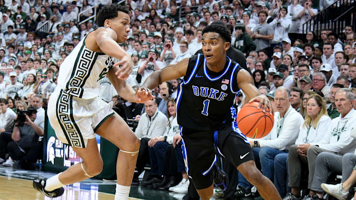 Dec 6, 2025; East Lansing, Michigan, USA;  Duke Blue Devils guard Caleb Foster (1) dribbles past Michigan State Spartans guard Divine Ugochukwu (99) during the first half at Jack Breslin Student Events Center. Mandatory Credit: Dale Young-Imagn Images