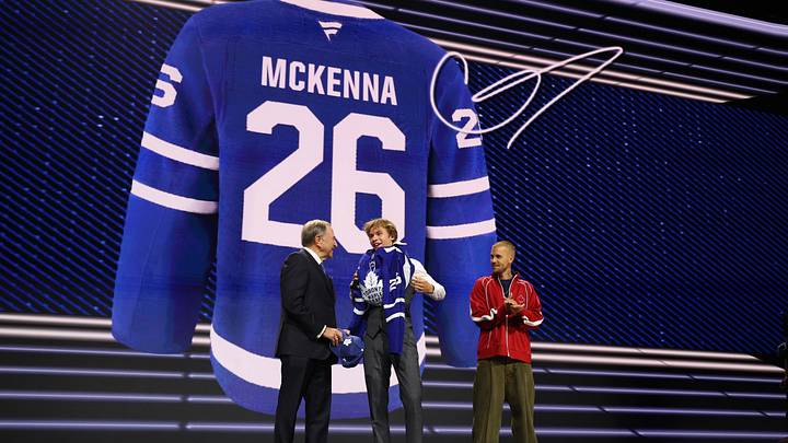 Jun 26, 2026; Buffalo, New York, USA; Gavin McKenna puts on a sweater beside NHL commissioner Gary Bettman and singer Justin Bieber after being selected with the first pick in the first round of the 2026 NHL Draft by the Toronto Maple Leafs at KeyBank Center. Mandatory Credit: Timothy T. Ludwig-Imagn Images
