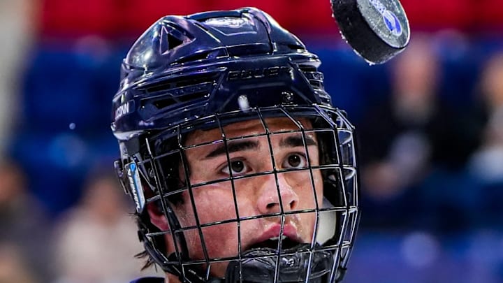 A University of Connecticut player eyes a Hockey East puck in the air. 