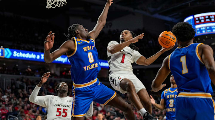 West Virginia Mountaineers center Eduardo Andre (0) blocks Cincinnati Bearcats guard Day Day Thomas (1) on his way to the basket in the second half of the NCAA basketball game between the Cincinnati Bearcats and the West Virginia Mountaineers at Fifth Third Arena in Cincinnati on Sunday, Feb. 2, 2025. The Bearcats lost, 63-50.