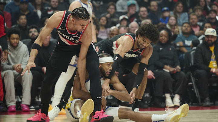 Apr 11, 2025; Portland, Oregon, USA; Golden State Warriors guard Moses Moody (4) gets tied up during the first half against Portland Trail Blazers forward Toumani Camara (33), left, and guard Matisse Thybulle (4) at Moda Center. Mandatory Credit: Troy Wayrynen-Imagn Images