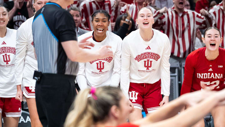 The Indiana Hoosiers bench celebrate an early charging call Friday, March 7, 2025, against the USC Trojans during the Big Ten women's tournament at Gainbridge Fieldhouse in Indianapolis. Sharnecce Currie-Jelks (left) and Henna Sandvik (right) are prominently featured in the photo.