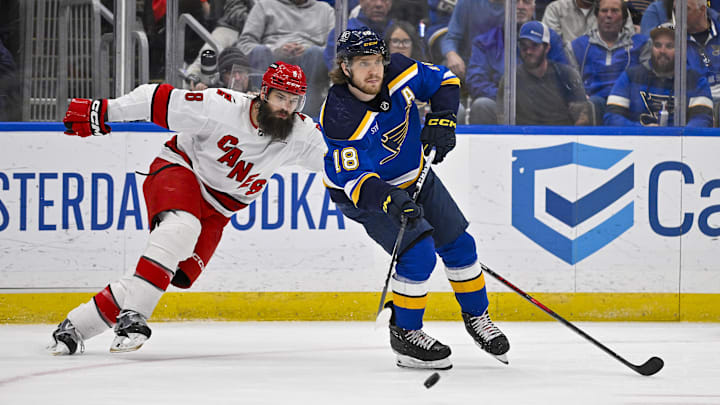 Apr 12, 2024; St. Louis, Missouri, USA;  St. Louis Blues center Robert Thomas (18) passes the puck as Carolina Hurricanes defenseman Brent Burns (8) defends during the third period at Enterprise Center. Mandatory Credit: Jeff Curry-USA TODAY Sports