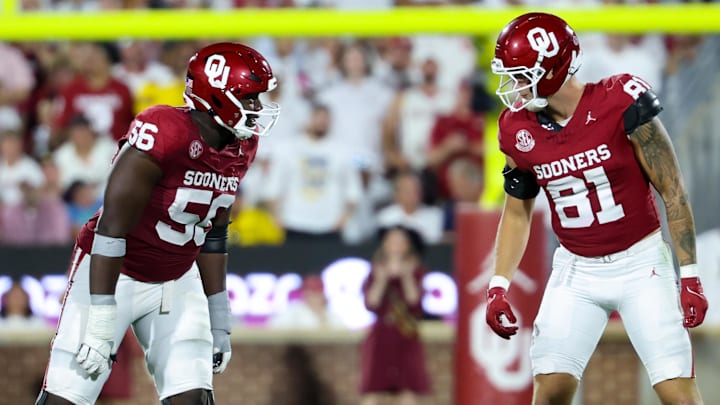 Oklahoma offensive lineman Michael Fasusi (56) communicates with  Sooners tight end Will Huggins (81) before a snap against Michigan.