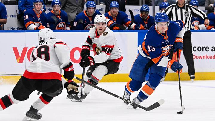 Jan 14, 2025; Elmont, New York, USA;  New York Islanders center Mathew Barzal (13) skates with the puck defended by Ottawa Senators center Tim Stützle (18) during the second period at UBS Arena. Mandatory Credit: Dennis Schneidler-Imagn Images