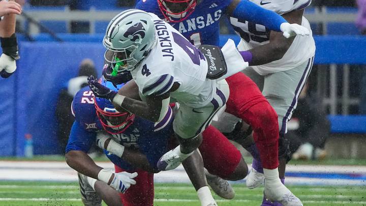 Oct 25, 2025; Lawrence, Kansas, USA; Kansas State Wildcats running back Joe Jackson (4) runs the ball as Kansas Jayhawks defensive tackle D.J. Withers (52) makes the tackle during the first half of the game at David Booth Kansas Memorial Stadium. Mandatory Credit: Denny Medley-Imagn Images