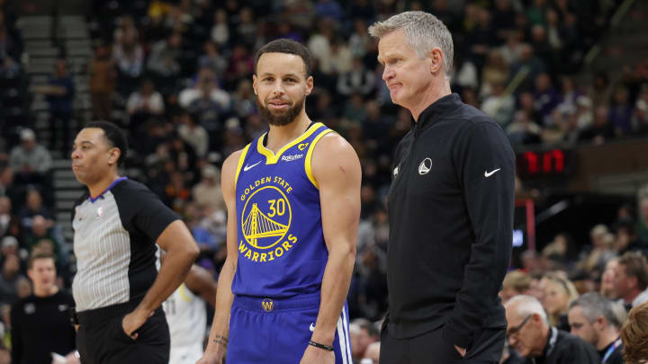 Warriors guard Steph Curry and head coach Steve Kerr talk on the sideline during the first quarter against the Utah Jazz at Delta Center.