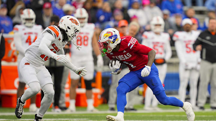 Nov 1, 2025; Lawrence, Kansas, USA; Kansas Jayhawks wide receiver Emmanuel Henderson Jr. (1) runs with the ball against Oklahoma State Cowboys cornerback Eric Fletcher (13) during the second half at David Booth Kansas Memorial Stadium. Mandatory Credit: Jay Biggerstaff-Imagn Images