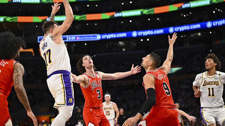 Mar 22, 2025; Los Angeles, California, USA; Los Angeles Lakers guard Luka Doncic (77) passes against Chicago Bulls guard Josh Giddey (3) and center Nikola Vucevic (9) during the first half at Crypto.com Arena. Mandatory Credit: Jonathan Hui-Imagn Images
