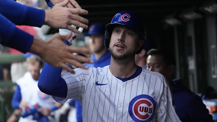 Chicago Cubs outfielder Kyle Tucker gives teammates a high five in the dugout in a white pinstriped jersey and a blue helmet. Chicago Cubs outfielder Kyle Tucker gives teammates a high five in the dugout in a white pinstriped jersey and a blue helmet.