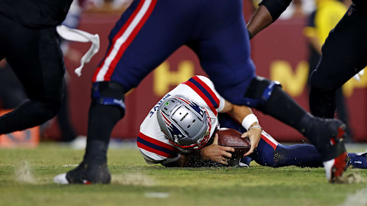 Aug 25, 2024; Landover, Maryland, USA; New England Patriots quarterback Drake Maye (10) recovers a fumble snap during the first quarter against the Washington Commanders during a preseason game at Commanders Field. Mandatory Credit: Peter Casey-USA TODAY Sports