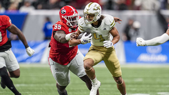 Nov 28, 2025; Atlanta, Georgia, USA; Georgia Tech Yellow Jackets wide receiver Isiah Canion (4) runs against Georgia Bulldogs defensive lineman Nnamdi Ogboko (95) during the second half at Mercedes-Benz Stadium. Mandatory Credit: Dale Zanine-Imagn Images