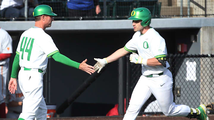 Oregon head baseball coach Mark Wasikowski, left, congratulates Brennan Milone as he heads to home