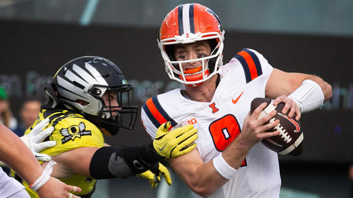 Oregon’s Bryce Boettcher, left, gets a hand on Illinois quarterback Luke Altmyer during the third quarter at Autzen Stadium.