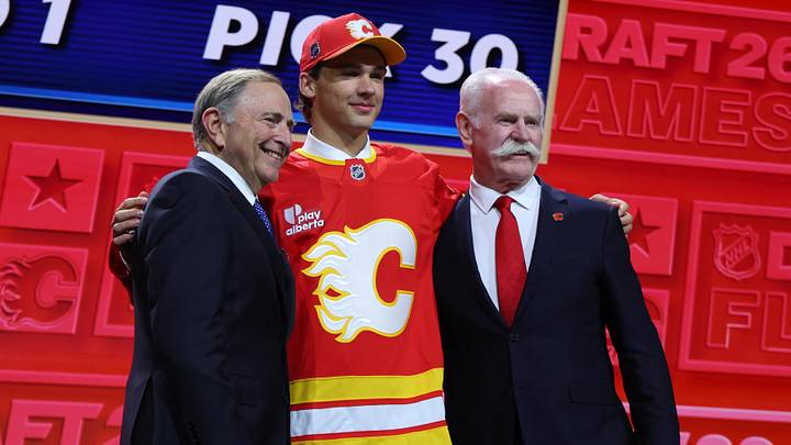 Jun 26, 2026; Buffalo, New York, USA; Jack Hextall reacts beside NHL commissioner Gary Bettman and former NHL player Lanny McDonald after being selected with the thirtieth pick in the first round of the 2026 NHL Draft by the Calgary Flames at KeyBank Center. Mandatory Credit: Timothy T. Ludwig-Imagn Images