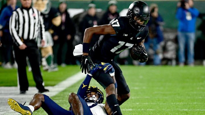 Oct 21, 2023; East Lansing, Michigan, USA;  Michigan State Spartans wide receiver Tre Mosley (17) pulls down a pass and Michigan Wolverines defensive back Makari Paige (7) pulls him down in the first quarter at Spartan Stadium. Mandatory Credit: Dale Young-Imagn Images