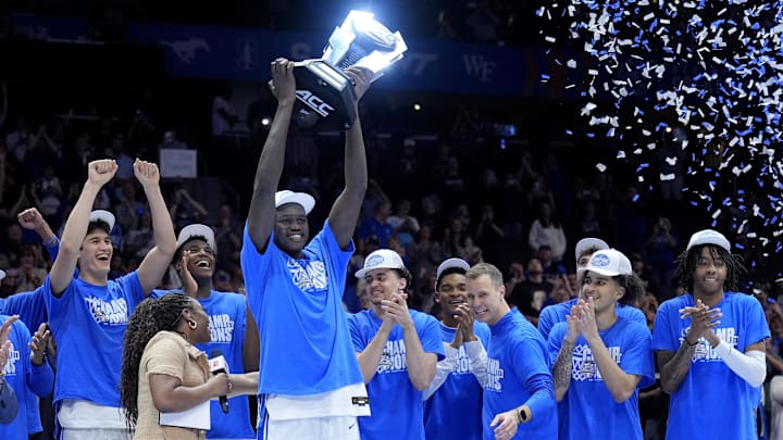 Mar 15, 2025; Charlotte, NC, USA; Duke Blue Devils center Khaman Maluach (9) holds the trophy and celebrates with head coach Jon Scheyer and teammates after winning the 2025 ACC Conference Championship game against the Louisville Cardinals at Spectrum Center. Mandatory Credit: Jim Dedmon-Imagn Images